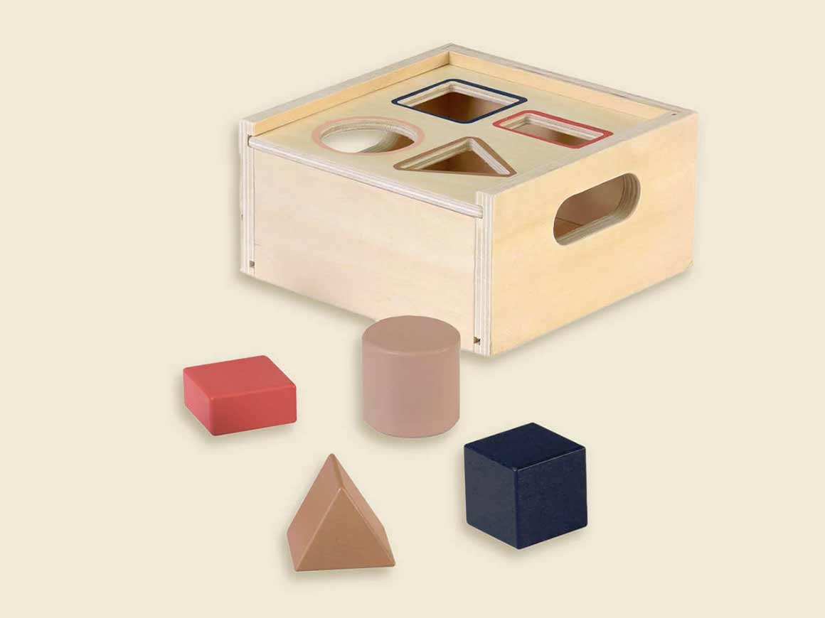 formensortierbox-holz-egmont-toys Formensortierbox aus Holz von Egmont Toys mit vier geometrischen Formen in Natur, Beige, Rot und Marineblau.